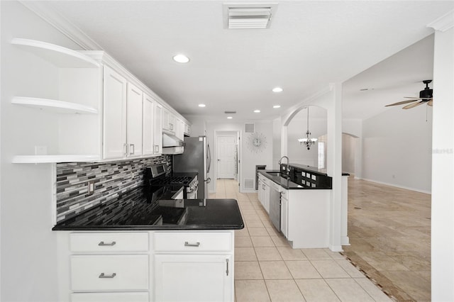 kitchen with light tile patterned floors, stainless steel appliances, ornamental molding, white cabinets, and ceiling fan with notable chandelier