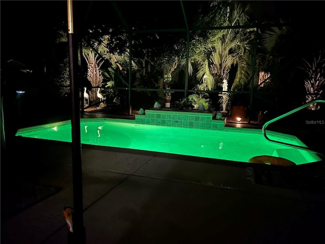 pool at twilight featuring a lanai