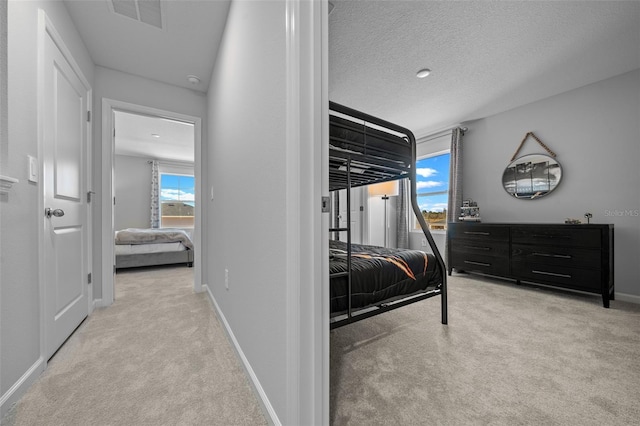 carpeted bedroom with a textured ceiling, visible vents, and baseboards