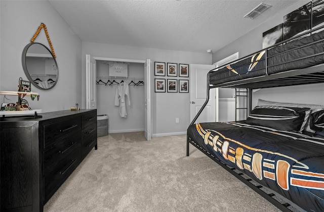 bedroom featuring baseboards, visible vents, light carpet, and a textured ceiling