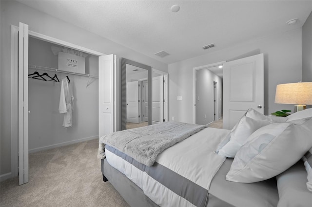 bedroom with light carpet, a closet, a textured ceiling, and visible vents