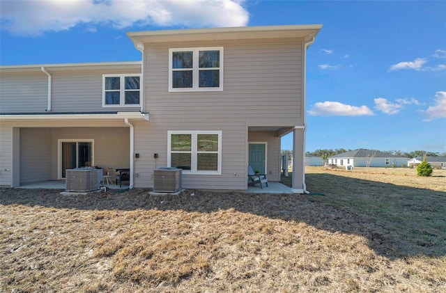 back of property with central air condition unit, a patio area, and a lawn