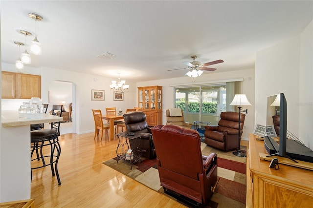 living room featuring ceiling fan with notable chandelier and light hardwood / wood-style flooring