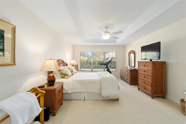 bedroom featuring ceiling fan, carpet floors, and a tray ceiling