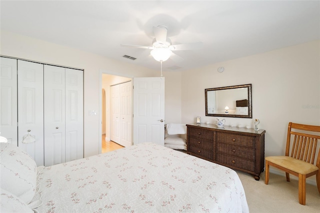 carpeted bedroom featuring ceiling fan and multiple closets