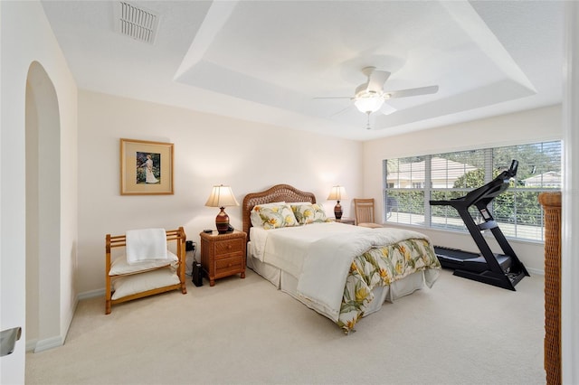 carpeted bedroom with a tray ceiling and ceiling fan