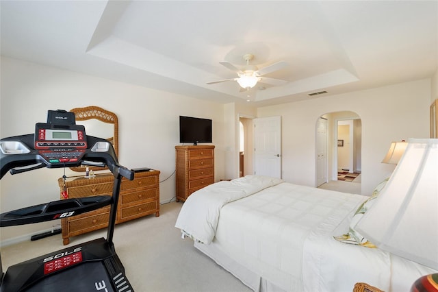 carpeted bedroom with ceiling fan and a tray ceiling