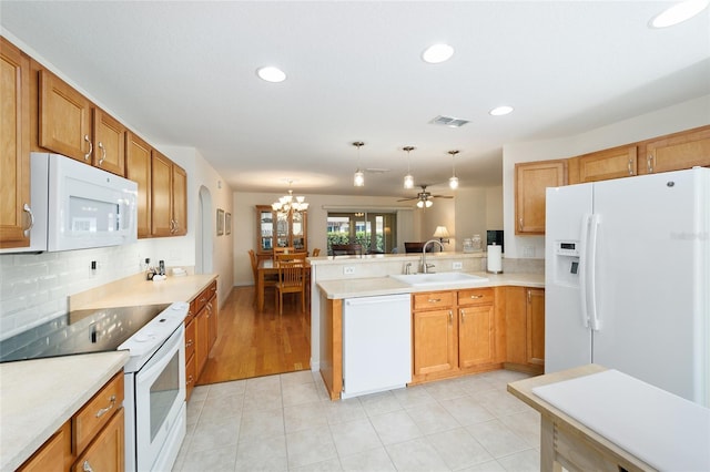 kitchen with sink, hanging light fixtures, backsplash, kitchen peninsula, and white appliances