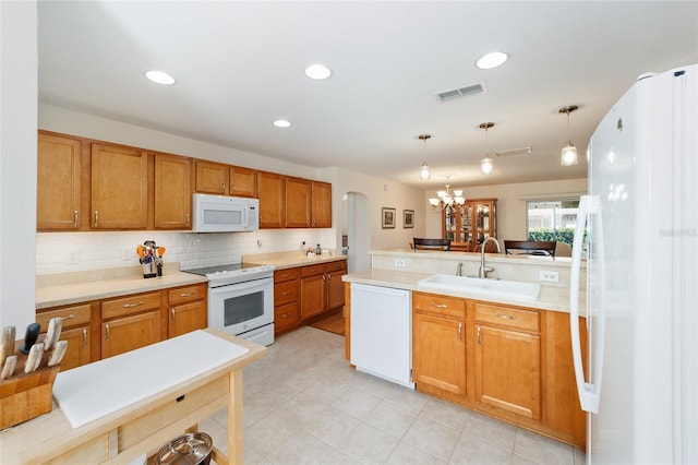 kitchen with white appliances, sink, decorative light fixtures, a notable chandelier, and kitchen peninsula