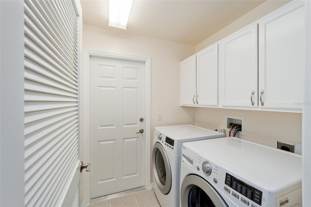 washroom featuring cabinets, light tile patterned floors, and washing machine and clothes dryer