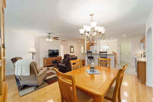 dining area featuring ceiling fan with notable chandelier and light wood-type flooring