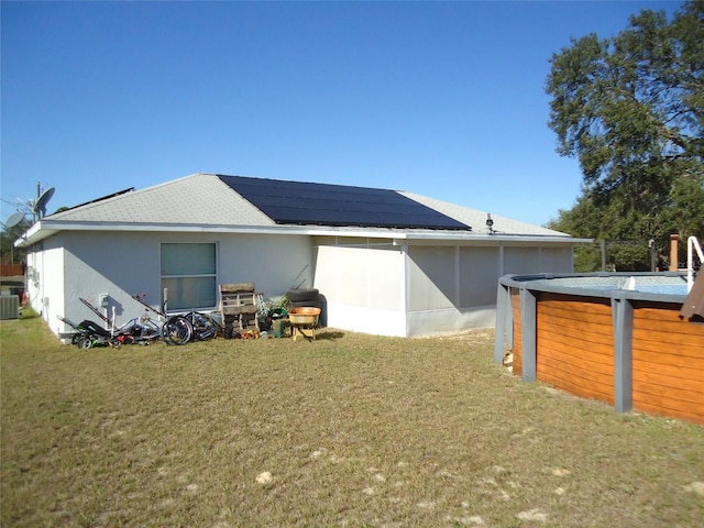 view of property exterior featuring central AC unit, a yard, and solar panels