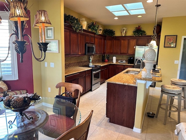 kitchen with tasteful backsplash, sink, a skylight, stainless steel appliances, and light tile patterned floors