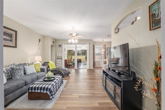 living room with ceiling fan, light hardwood / wood-style floors, and a textured ceiling