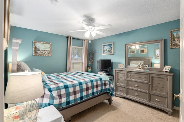 bedroom with ceiling fan, light carpet, and a textured ceiling