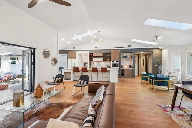 living room featuring light hardwood / wood-style floors, ceiling fan, and vaulted ceiling with skylight