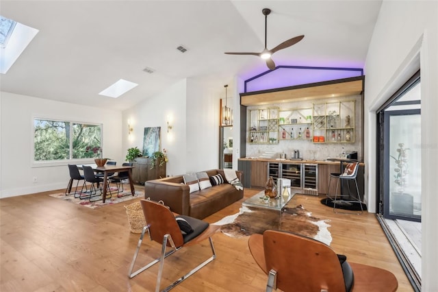 living room featuring indoor bar, light hardwood / wood-style flooring, ceiling fan, and lofted ceiling