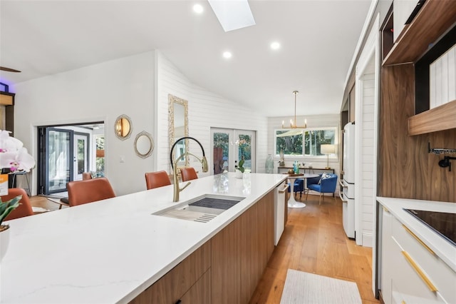 kitchen with sink, french doors, hanging light fixtures, white fridge, and white cabinets