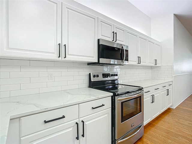 kitchen with white cabinets, backsplash, light stone counters, and stainless steel appliances