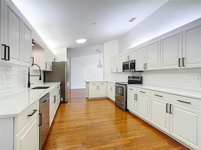 kitchen featuring white cabinets, stainless steel appliances, and hanging light fixtures