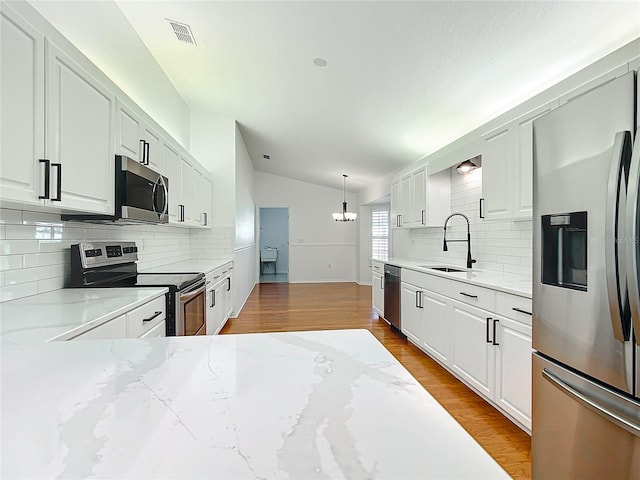 kitchen featuring sink, white cabinetry, stainless steel appliances, and vaulted ceiling