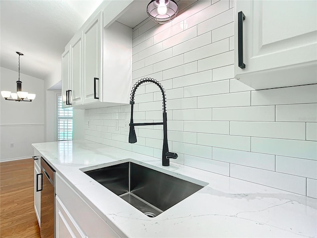 kitchen with decorative backsplash, white cabinets, light stone counters, and sink