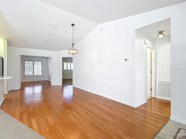 unfurnished living room with a chandelier, wood-type flooring, and vaulted ceiling