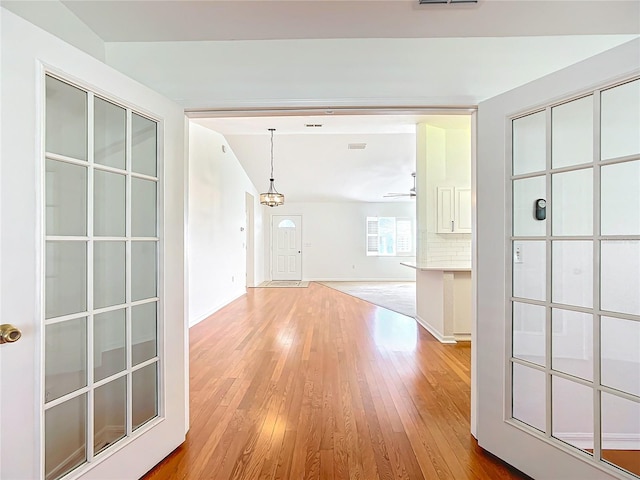 hall featuring a chandelier, vaulted ceiling, and hardwood / wood-style flooring