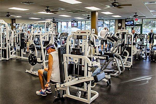 gym featuring a paneled ceiling, ceiling fan, and a wall of windows