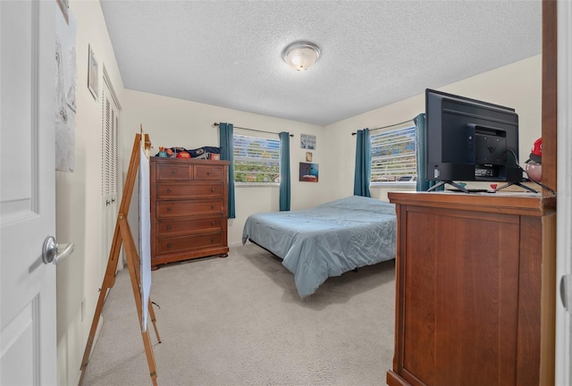 bedroom featuring light carpet and a textured ceiling