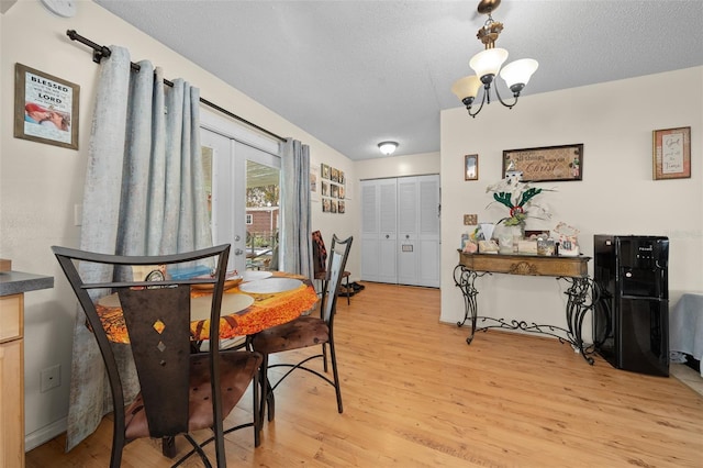 dining space featuring an inviting chandelier, a textured ceiling, and light wood-type flooring