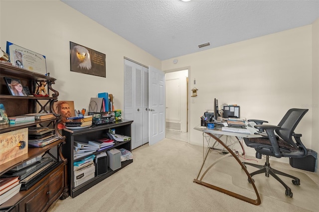 carpeted home office featuring a textured ceiling