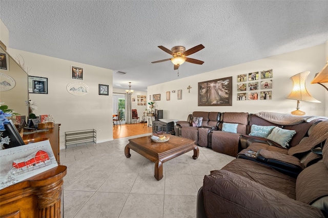 tiled living room featuring a textured ceiling and ceiling fan with notable chandelier