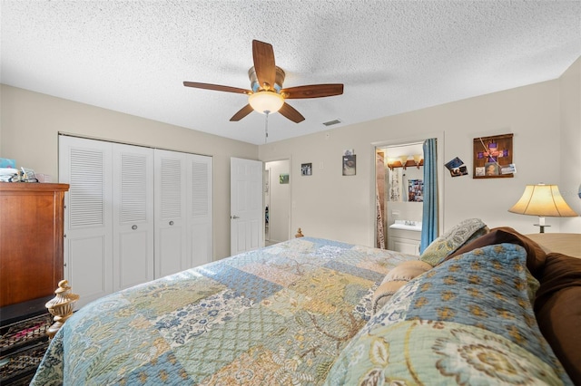 bedroom featuring ceiling fan, ensuite bathroom, a textured ceiling, and a closet