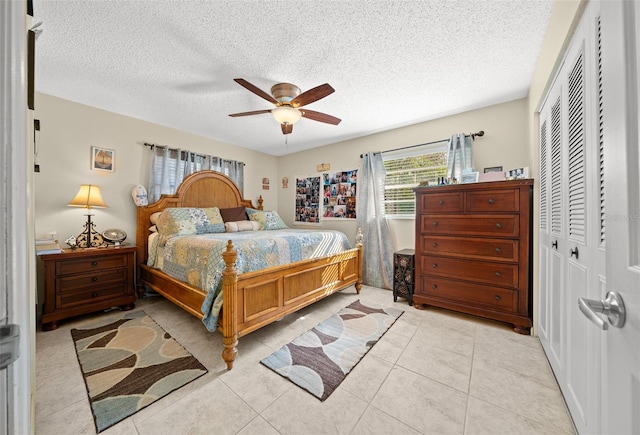 tiled bedroom featuring ceiling fan, a closet, and a textured ceiling