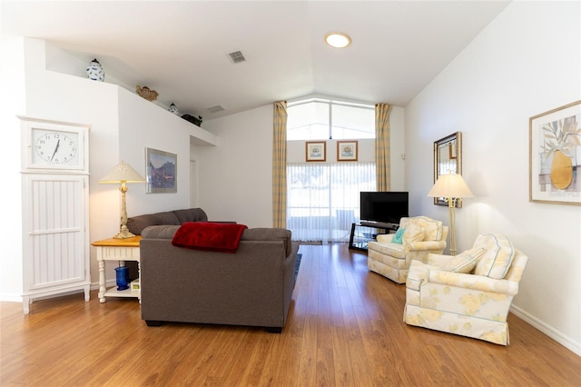 living room featuring wood-type flooring and vaulted ceiling