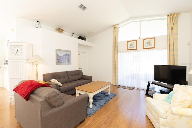 living room featuring light wood-type flooring, vaulted ceiling, and a wealth of natural light