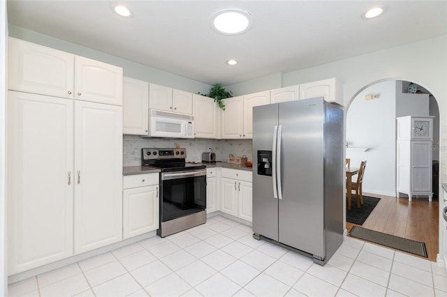 kitchen with tasteful backsplash, light tile patterned flooring, white cabinets, and stainless steel appliances