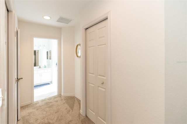 hallway featuring light colored carpet and sink