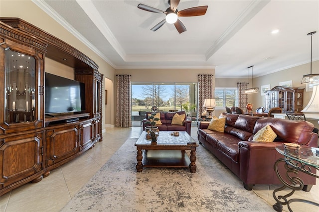 living room featuring a raised ceiling, ceiling fan, light tile patterned floors, and ornamental molding