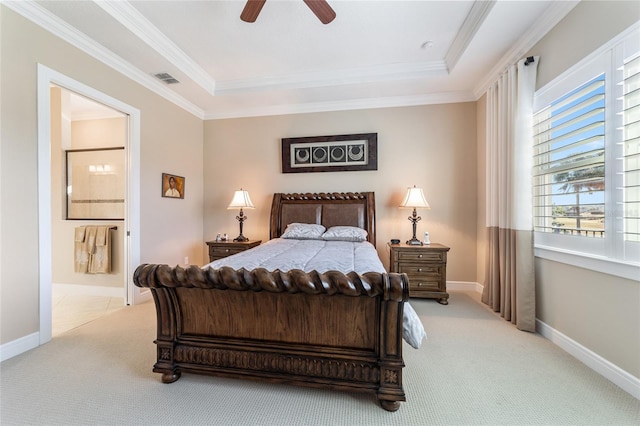 bedroom featuring a tray ceiling, ensuite bathroom, ceiling fan, and light colored carpet