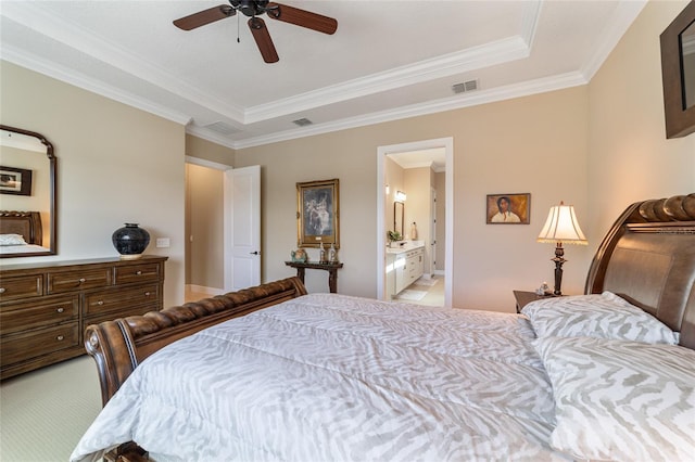 bedroom with a tray ceiling, ensuite bath, ceiling fan, and ornamental molding