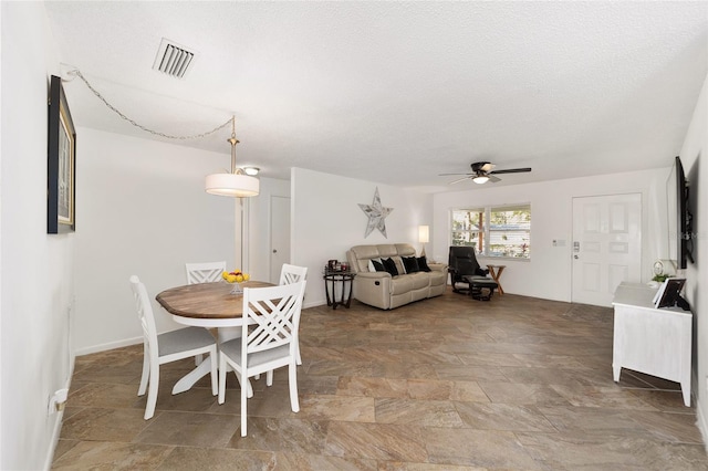 dining space featuring ceiling fan and a textured ceiling