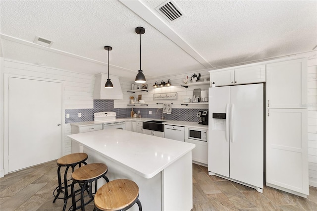 kitchen with white cabinets, a kitchen breakfast bar, white appliances, and sink