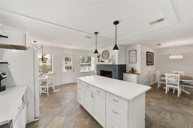 kitchen with white cabinetry, a kitchen island, hanging light fixtures, and a brick fireplace