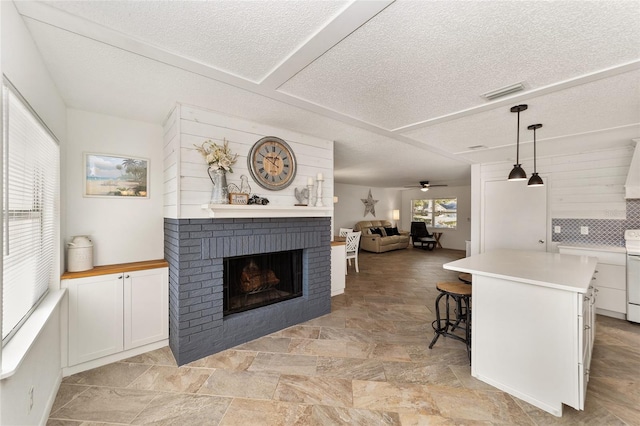 living room featuring a fireplace, a textured ceiling, and ceiling fan