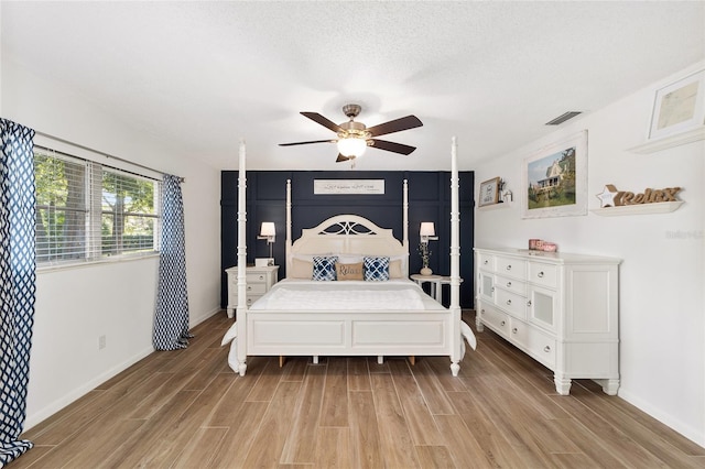 bedroom with a textured ceiling, light wood-type flooring, and ceiling fan