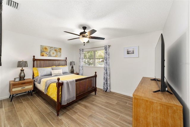 bedroom with ceiling fan, a textured ceiling, and hardwood / wood-style flooring