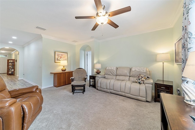 living room with crown molding, ceiling fan, and light carpet