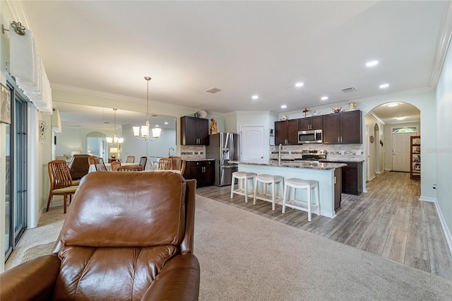 living room with a notable chandelier, crown molding, light wood-type flooring, and sink